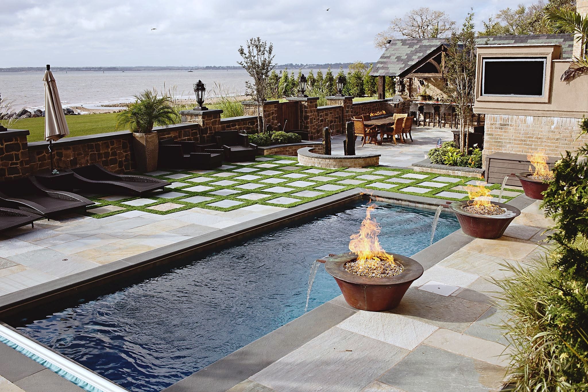 Waterfront pool with fire bowls, stone patio and turf-joint pavers
